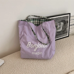 Detail of purple canvas tote bag with Bonjour magic print and green checkered lining