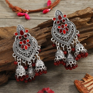 Detail of silver bohemian tassel earrings with red beads on a rustic wooden background