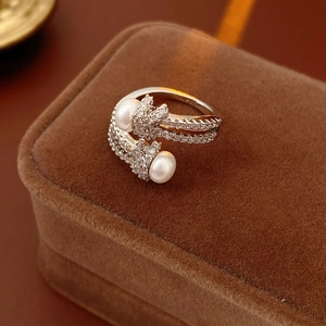 Close-up of knot design open ring with white pearls and pavé cubic zirconia