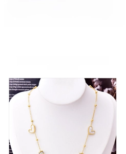Detail of titanium gold chain featuring white shell heart pendants and gold beads
