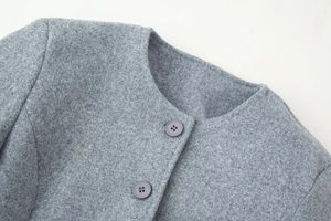Close-up of grey wool coat neckline showing fine fabric texture and button details