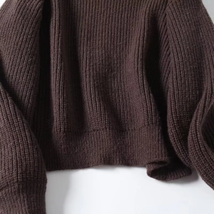 Detailed close-up of dark brown chunky knit sweater showing rib-knit hem and texture
