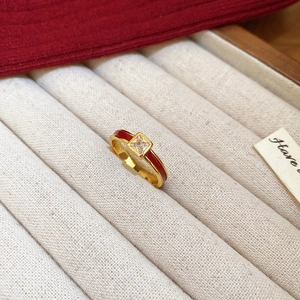 Detail of gold plated ring with red enamel and square zircon in a jewelry box