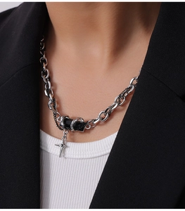 Detailed close-up of a silver punk cross pendant necklace worn with a black formal blazer