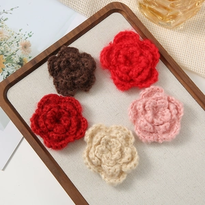 Five assorted hand-crocheted 7cm three-layer yarn flowers in a rustic wooden tray display
