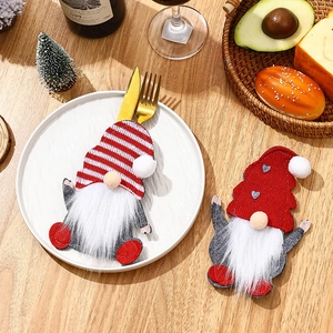 Detail of Christmas gnome cutlery holders on a festive table with red wine and decor