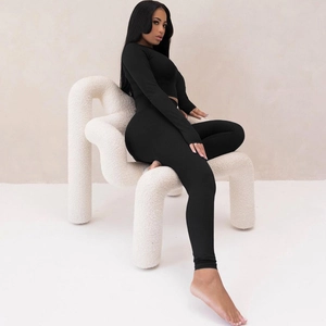 Detail of slim-fit black two-piece yoga set featuring long sleeve crop top and high-waist pants