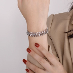 Detail of a silver double-layered curb chain bracelet with high-polish metallic finish