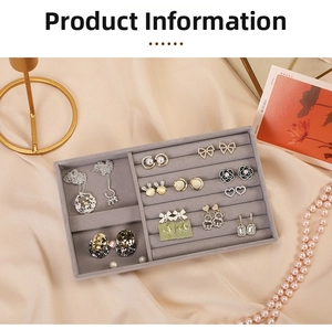 Detailed top view of grey velvet jewelry tray with ear studs and necklaces on silk fabric