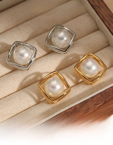Dettaglio di orecchini geometrici quadrati con perle in finitura oro e argento