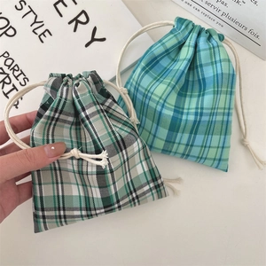 Close-up of hand-held plaid drawstring pouches showing woven texture and size