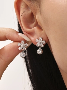 Gros plan de boucles d'oreilles fleur avec zircons scintillants portées par un mannequin