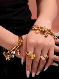 Detail of 18k gold plated bracelet with bear and heart charms on woman's hand