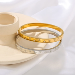 Polished stainless steel zircon star bangles in gold and silver on ceramic stand