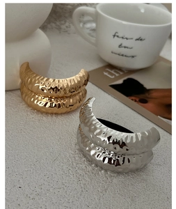 Detail of gold and silver geometric earrings with hammered texture on a styled background