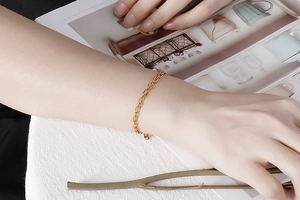 Close-up of a minimalist gold geometric chain bracelet worn on a model wrist