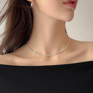 Detail of 925 sterling silver beaded necklace with tiny cross charm on female model