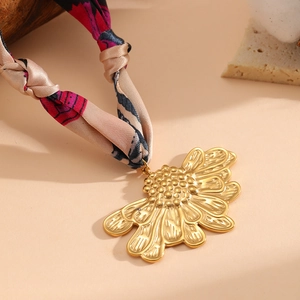 Dettaglio di un ciondolo floreale placcato oro 18K su una collana di nastro in seta