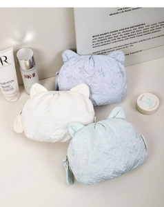 Three cat-ear makeup bags with floral embroidery in cream, blue, and mint colors