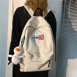 White canvas backpack with China embroidery and duck pendant shown on model back