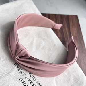 Detailed view of dust pink satin headband featuring a chic twisted knot and elegant luster