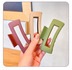 Detail view of large matte rectangular hair claws in burgundy, beige and green colors