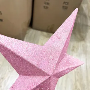Close-up of a pink glitter Christmas tree topper star with textured sequin finish
