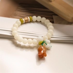 White Bodhi seed beaded bracelet with lotus pendant and green spacers on a smooth surface