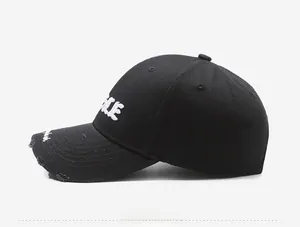 Detail of distressed brim and white letter embroidery on black vintage baseball cap