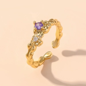 Makroaufnahme von unregelmäßigem Goldring mit lila Zirkon und Vier-Krallen-Fassung