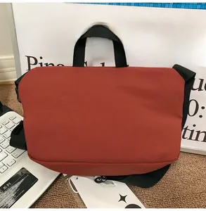 Detail of red minimalist nylon messenger bag with adjustable shoulder strap and tag