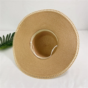 Detailed top view of large brim straw hat with hollow lace weave and windproof strap