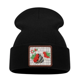 Black knit beanie with a strawberry cake patch featuring a minimalist creative design