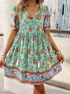 Detail of V-neckline with buttons and white tassels on green floral bohemian dress