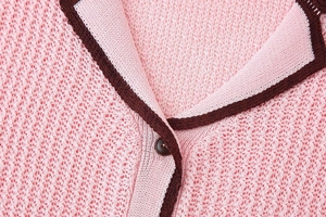 Detail of pink mesh knit cardigan featuring contrast brown trim and a single button