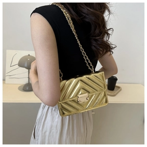 Detail of gold chain strap and V-quilted metallic texture on a small square bag