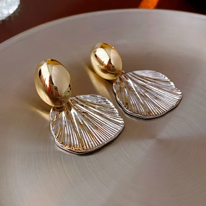 Detailed close-up of shell-textured silver and gold mixed metal stud earrings