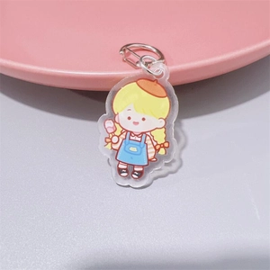 Detail of cute acrylic keychain girl with yellow hat and blue apron on pink dish