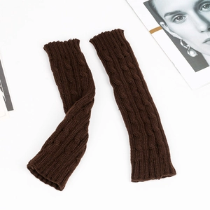 Close-up of dark brown cable knit arm warmers showing thick wool texture on white background