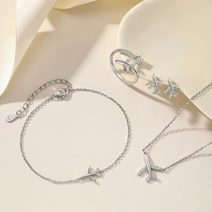 Macro shot of silver airplane jewelry set including necklace, bracelet and ring