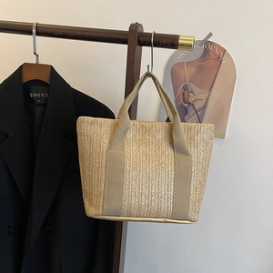 Detailed view of handmade straw woven tote bag with herringbone texture on wooden hanger