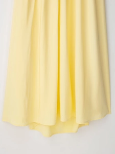 Gros plan détaillé du tissu plissé jaune et du drapé fluide de cette robe d'été