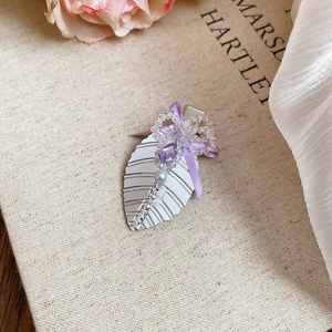 Détail d'une barrette fleurie avec nœud en ruban violet et strass scintillants