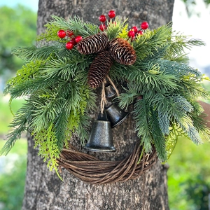 Bohemian Christmas wreath with pine branches, pinecones and bronze bells on a rustic base