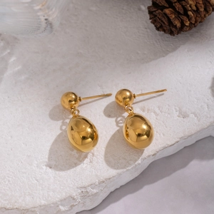 Macro detail of gold-plated teardrop earrings showing polished mirror finish and round studs