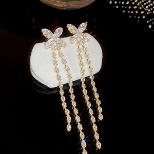 Macro shot of gold butterfly tassel earrings with sparkling cubic zirconia on a stand