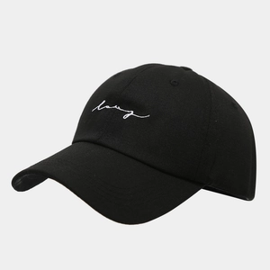 Detail of black cotton baseball cap showing white script embroidery and breathable eyelets