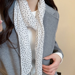 Detail shot of a polka dot scarf necklace made of lightweight chiffon on a grey wool coat