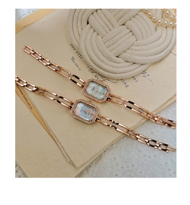 Detail of elegant rose gold square watch with diamond bezel and mother of pearl dial