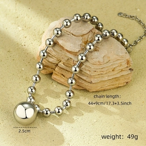 Macro detail of silver beaded necklace with a large 2.5cm polished metal ball pendant